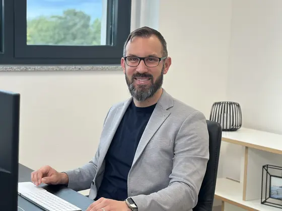 Simon Tiffert smiling at his desk in the OptaZEN office
