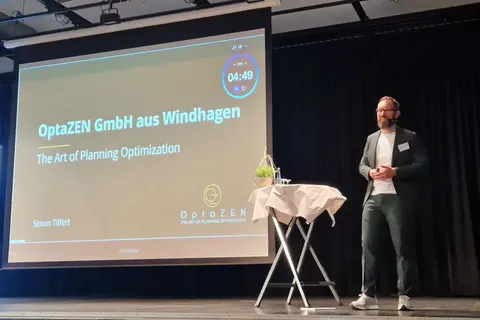 Simon Tiffert on stage at the Business Breakfast of Verbandsgemeinde Asbach, with the slide "OptaZEN GmbH aus Windhagen" behind him
