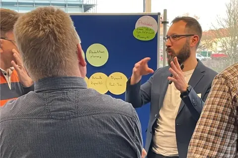 Simon Tiffert in the production working group at a pinboard with cards on production planning, staff capacity and dynamic planning